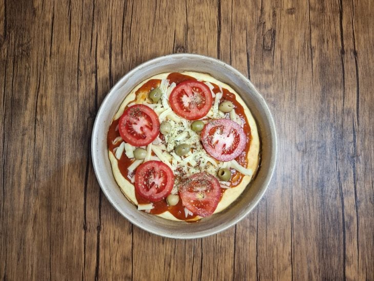 Pizza recheada com tomates, queijos e azeitonas.