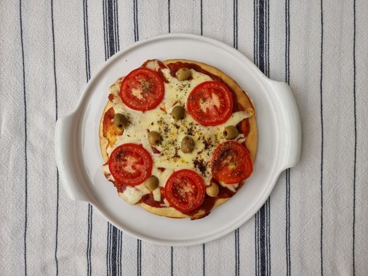 Pizza servido em recipiente de cor branca.