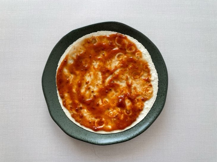 Molho de tomate espalhado sobre a massa.