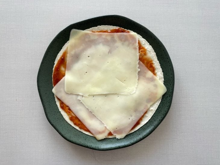 Fatias de queijo distribuídas sobre a massa.