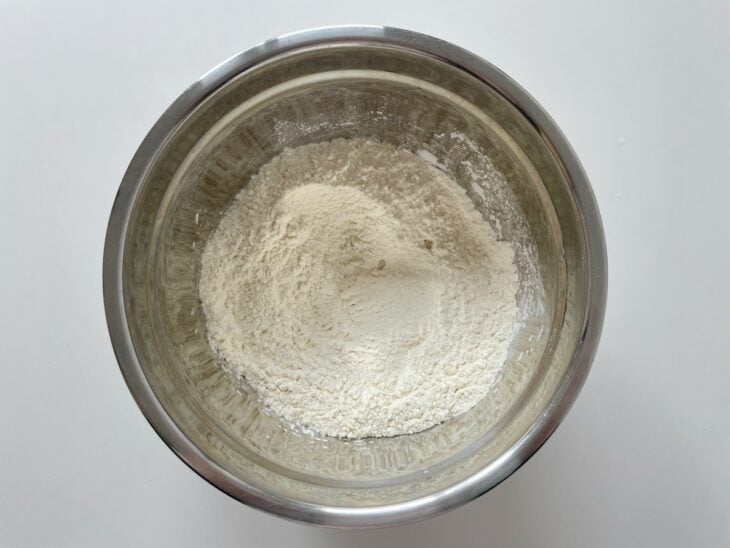 Farinha de trigo, azeite e sal sendo misturados na batedeira com o gancho de massas pesadas.