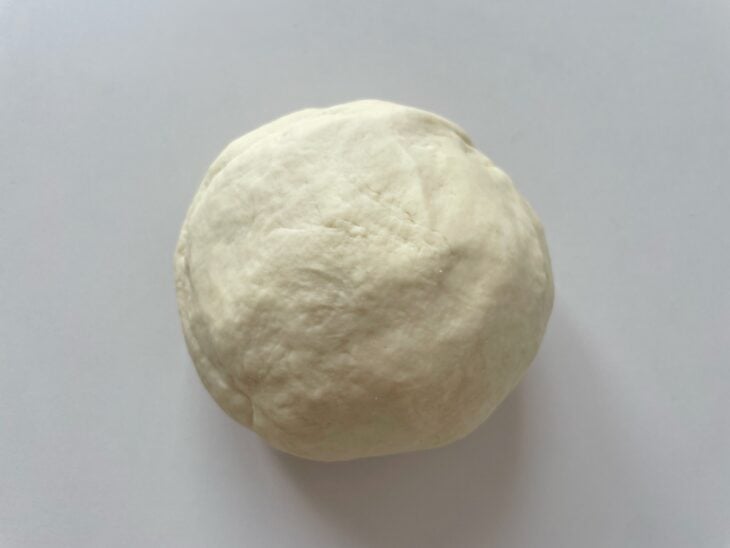 Mistura líquida com fermento sendo derramada na tigela da batedeira junto aos ingredientes secos.