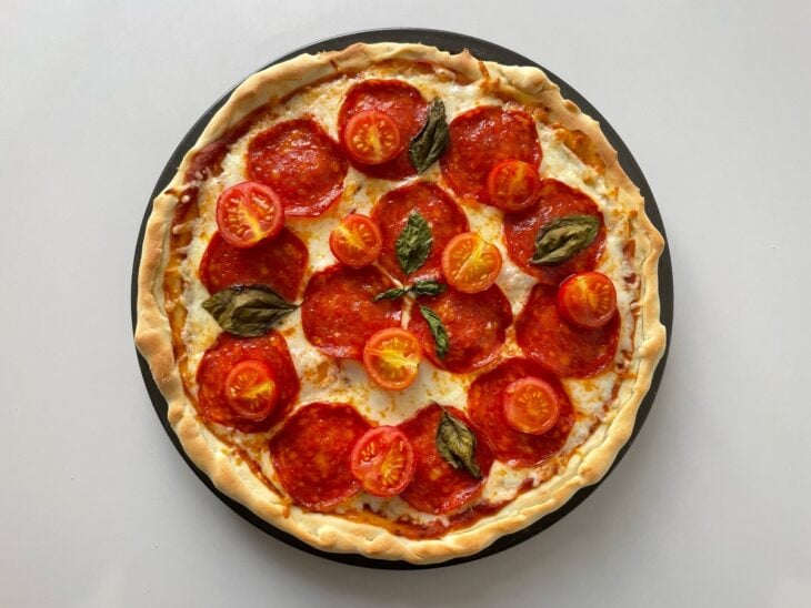 Pizza de pepperoni retirada do forno com as bordas douradas e o queijo borbulhando.