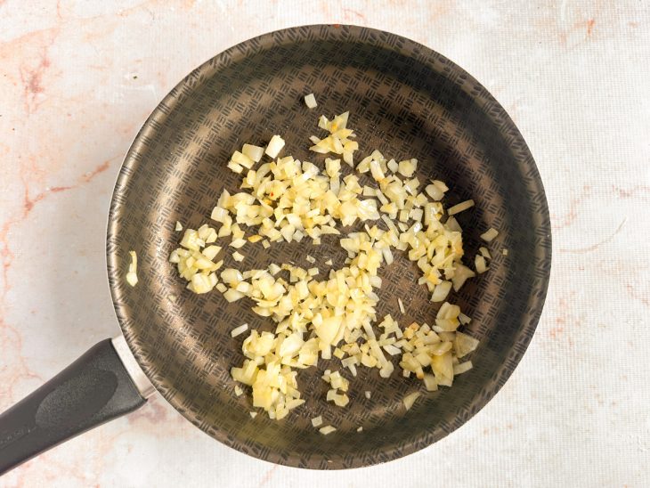 Cebola refogando na panela até ficar transparente.