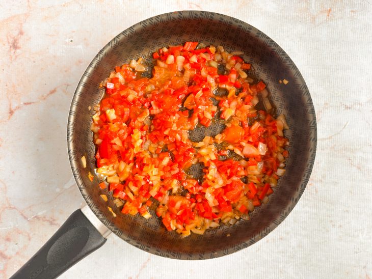 Pimentão e extrato de tomate sendo incorporados ao refogado.