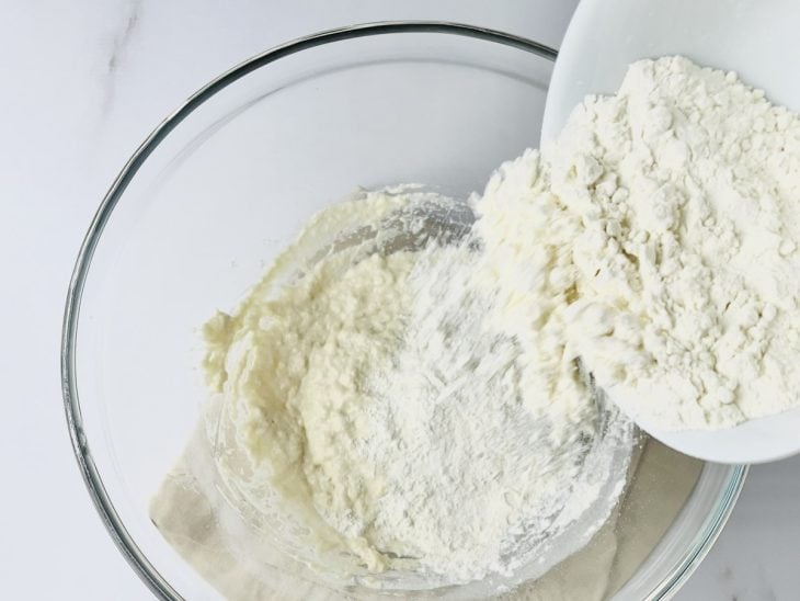 Uma tigela com fermento, água morna, açúcar, azeite, sal e farinha.