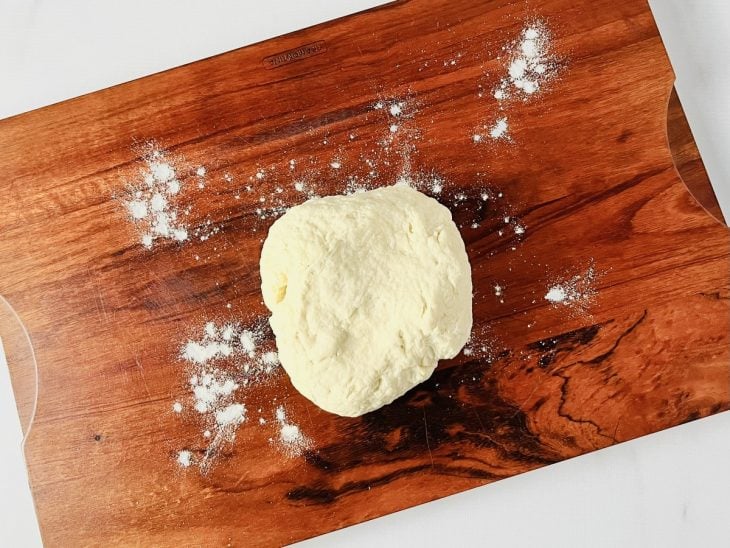 Uma tábua com a massa da pizza sovada.