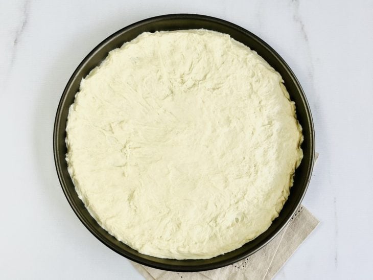 Uma assadeira com a massa da pizza.