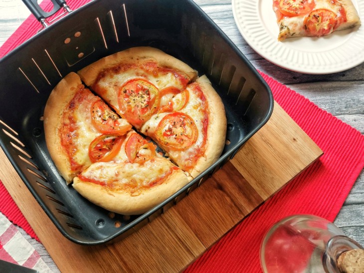 Uma cesta de airfryer contendo uma pizza.