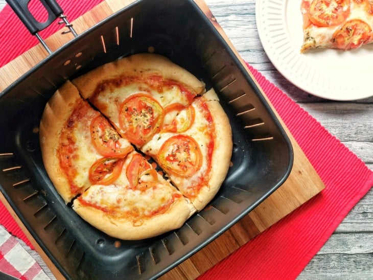 Uma cesta de airfryer contendo uma pizza.