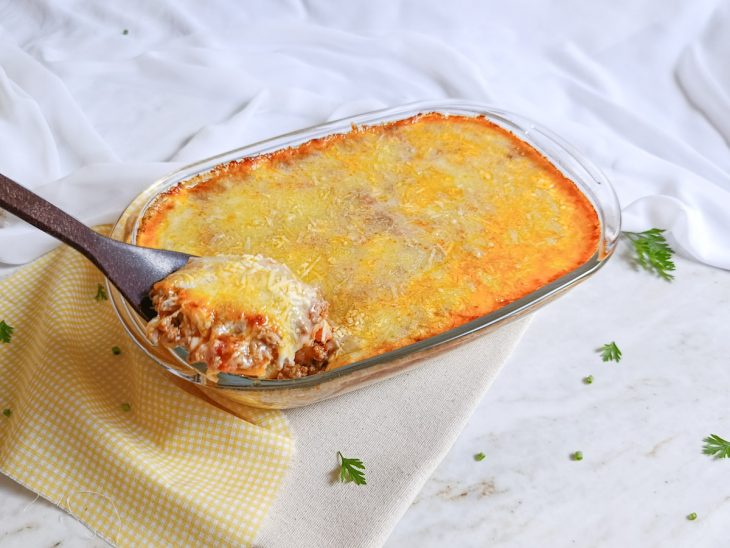 Porção de polenta cremosa com carne moída sendo retirada.