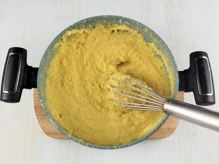 Polenta em textura cremosa na panela.
