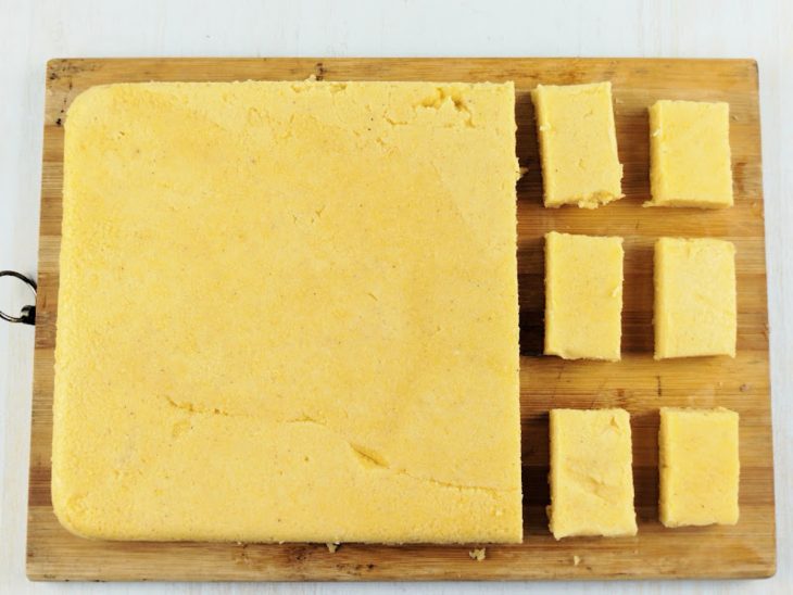 Polenta cortada em tiras sobre uma tábua.