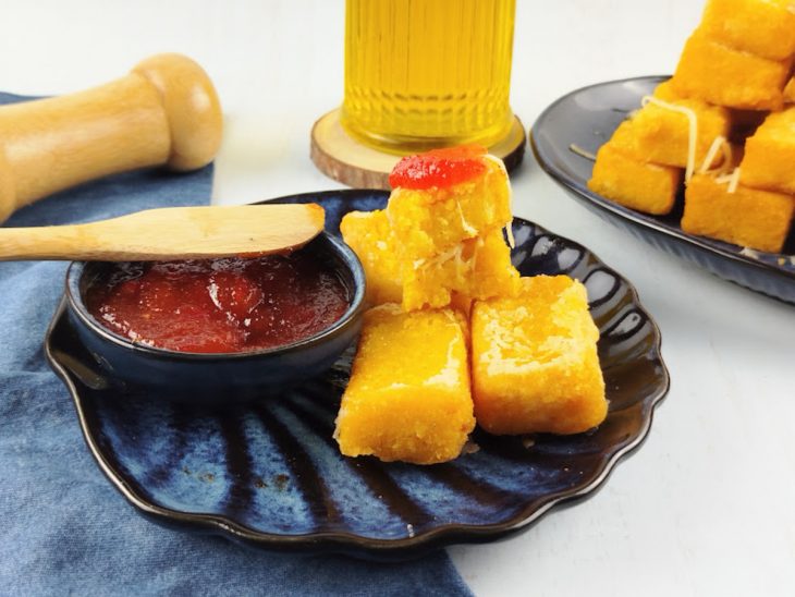 Polenta frita servida acompanhada por molho.