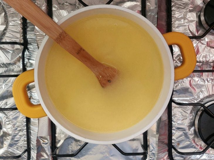 Uma panela com água, manteiga, sal, noz-moscada e fubá.