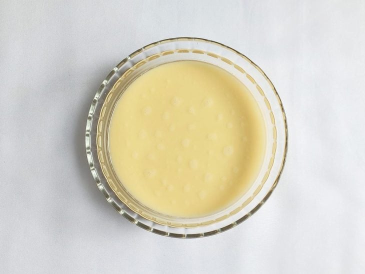 Fubá dissolvido em água num recipiente redondo de vidro.