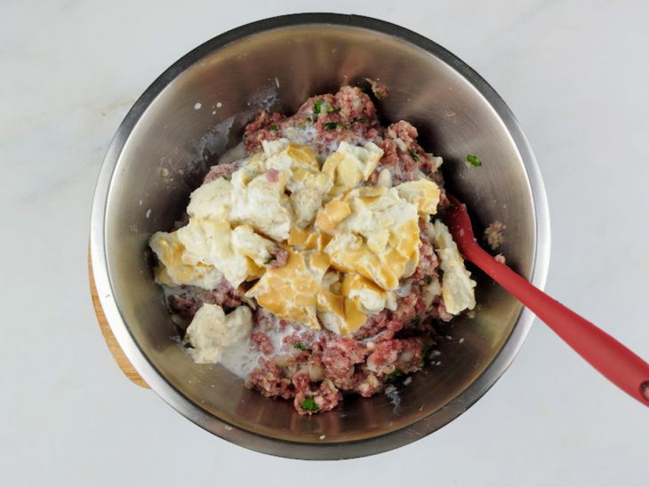 Mistura de pão e leite adicionada na tigela com carne temperada.