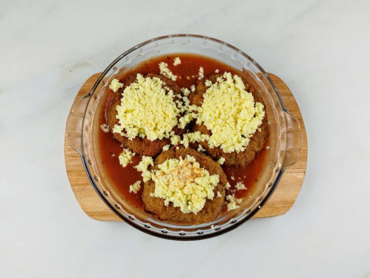 Queijo e parmesão salpicados sobre os polpetones na tigela.