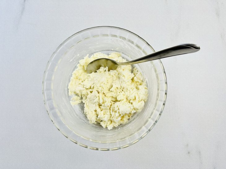 Cream cheese e mussarela misturados em um recipiente de vidro.