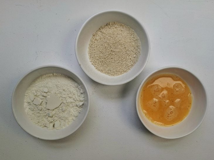 Ovo, farinha de trigo e farinha Panko em recipientes distintos.