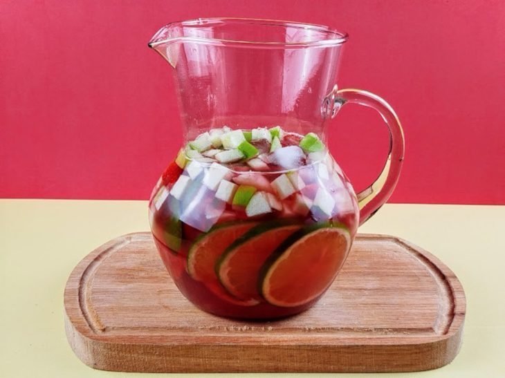 Jarra com chá gelado, frutas picadas, folhas de hortelã e gelo.