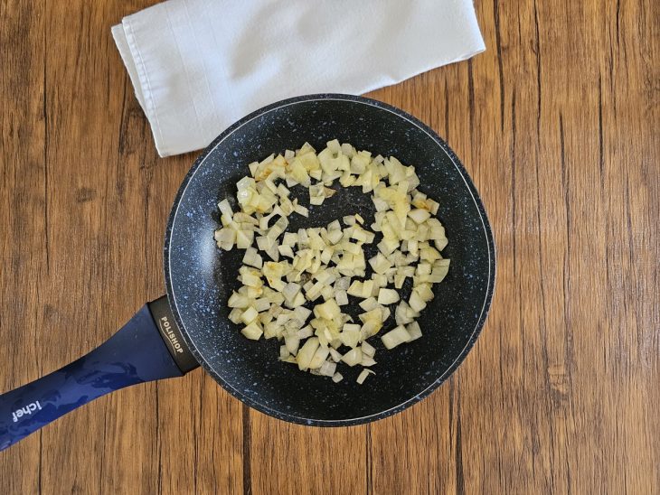 Uma frigideira refogando a cebola.