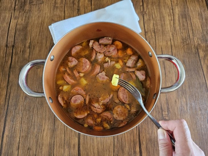 Uma panela cozinhando legumes e carnes.