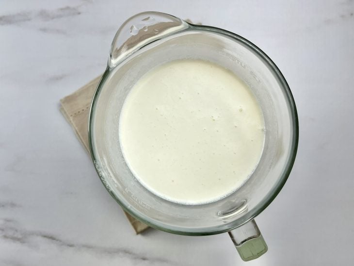 Um liquidificador contendo a mistura de leite condensado, creme de leite, leite, gelatina hidratada e essência de baunilha.