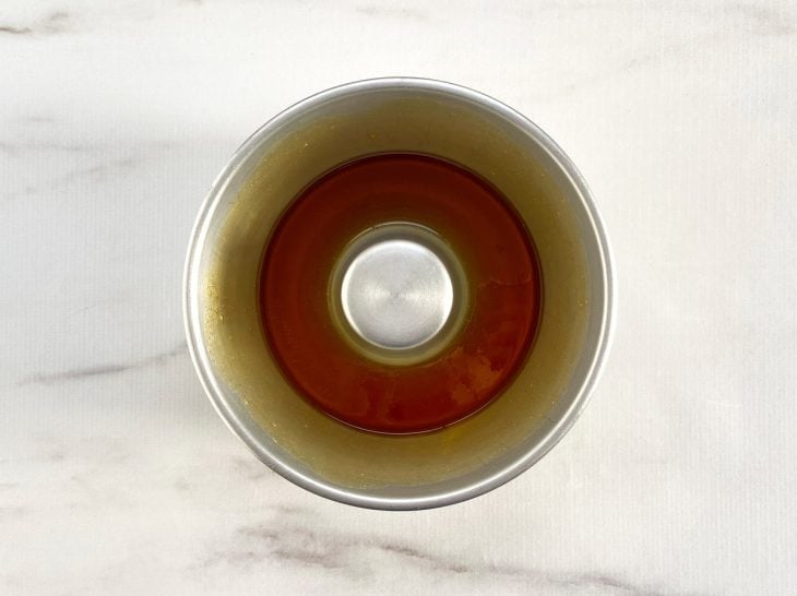 Forma de pudim com a calda espalha no fundo e nas laterais.