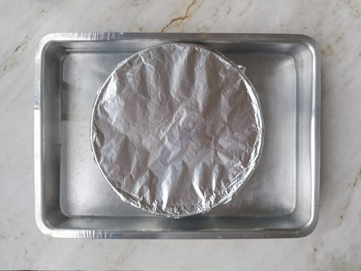 Forma coberta na assadeira com água.