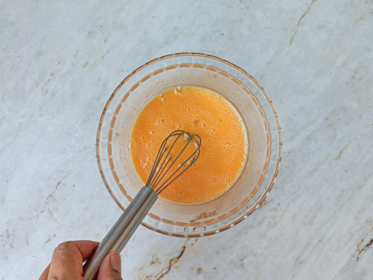 Numa tigela, os ovos batidos com fouet e o adoçante culinário.