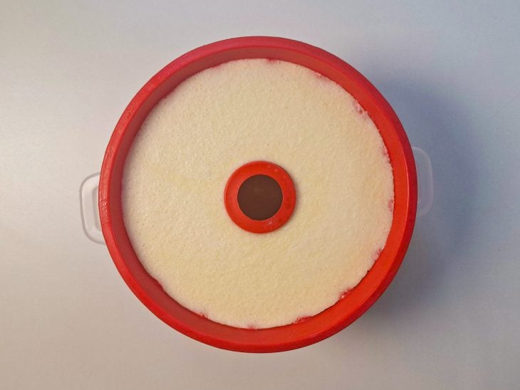 Camada de pudim de coco adicionada por cima a de chocolate na forma.