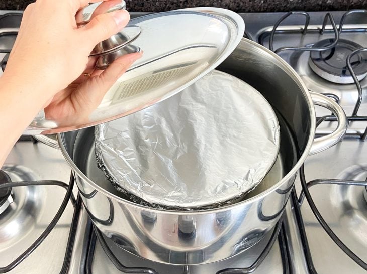 Uma forma dentro da panela com água ao fogo.