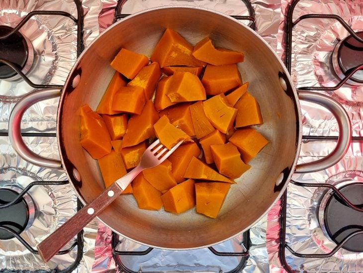 Uma panela cozinhando abóbora em pedaços.