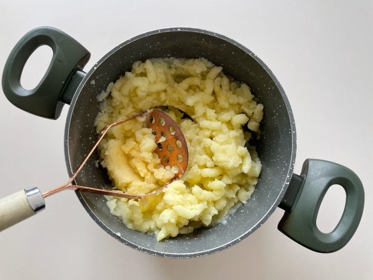 Batatas sendo amassadas na panela.