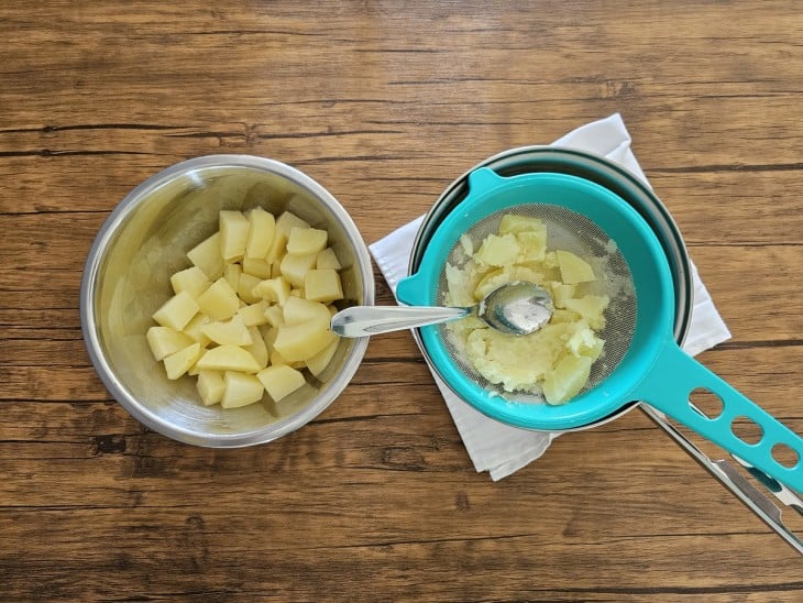 Batatas cozidas sendo amassadas.