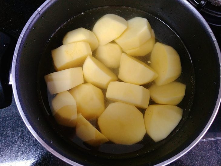 Panela com batatas cortadas cobertas por água.