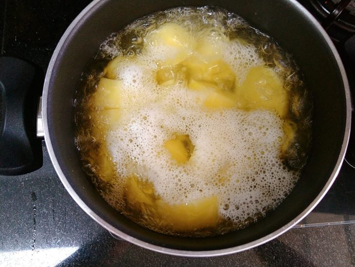 Panela com batatas e água borbulhando.