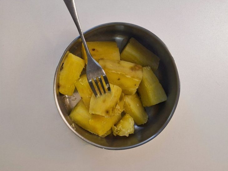Batata-doce cortada em pedaços sendo preparada para o cozimento.