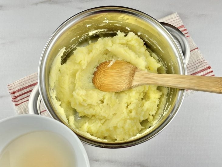 Uma panela com batatas amassadas, azeite e caldo de legumes.