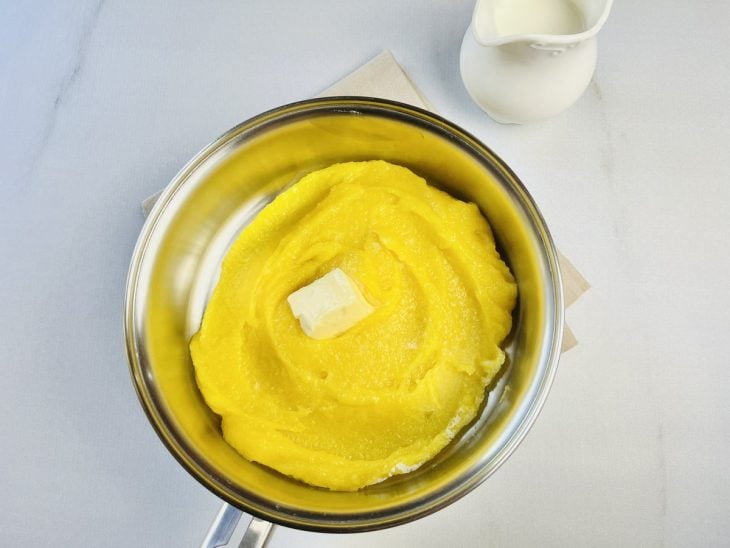 Purê de mandioquinha na panela com leite, manteiga e sal.