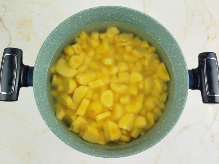 Mandioquinhas picadas com água e sal numa panela.