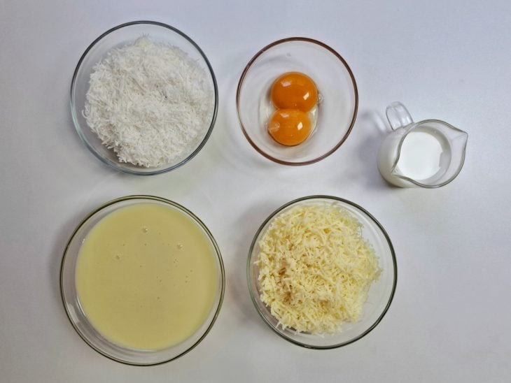 Ingredientes para a receita de queijadinha reunidos em uma superfície.