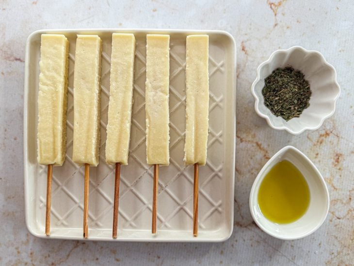 Ingredientes organizados sobre a bancada com os espetos de queijo coalho.