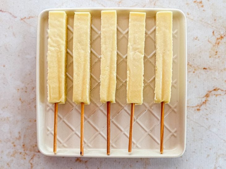 Espetos de queijo sendo preparados para caber na cesta da air fryer.