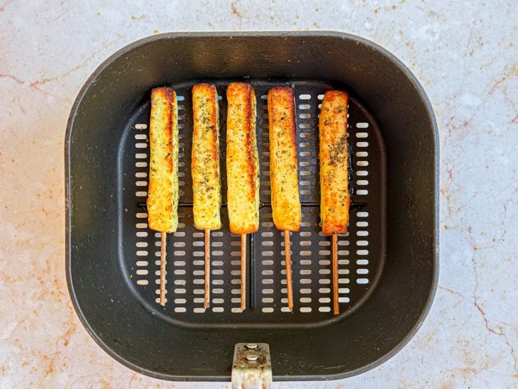 Queijos dourando na air fryer em temperatura mais alta para formar crosta.