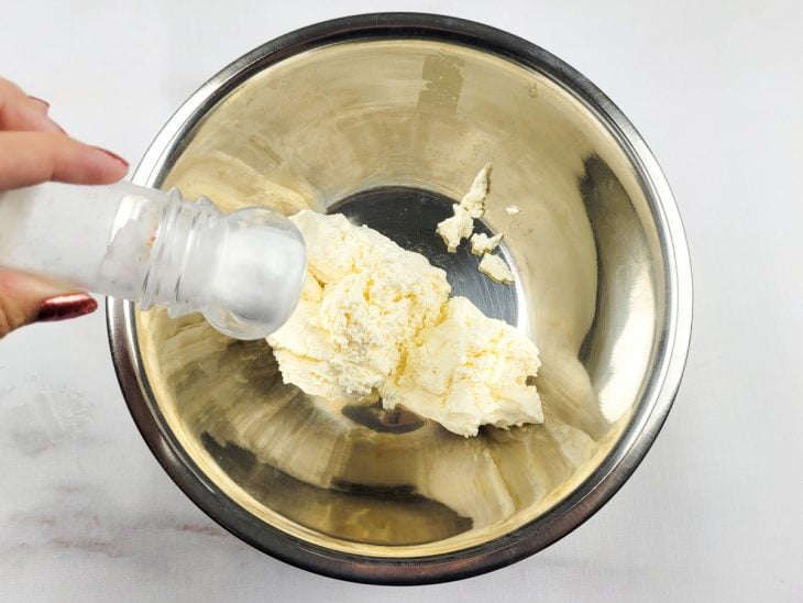 Um recipiente contendo o queijo sendo temperado.