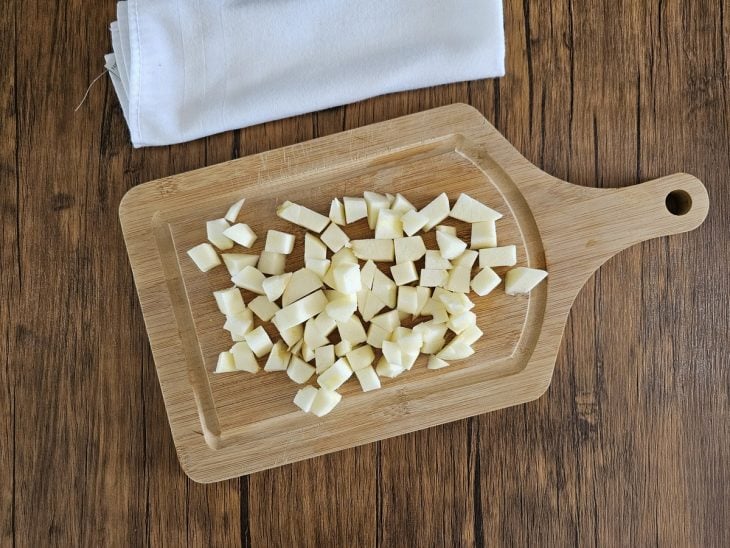 Tábua com maçãs cortadas em cubos pequenos.