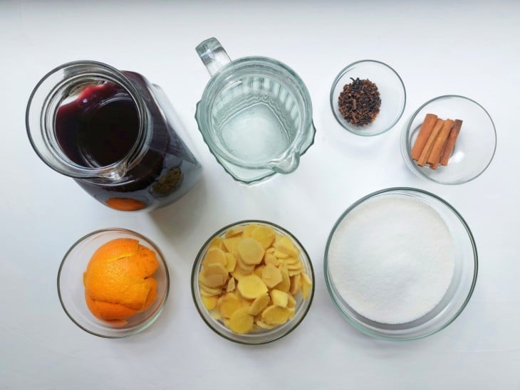 Ingredientes reunidos: gengibre, canela, açúcar, água, cravos, suco de uva e cascas de laranja.