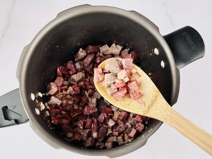 Carne de boi, alho e cebola adicionada a panela.